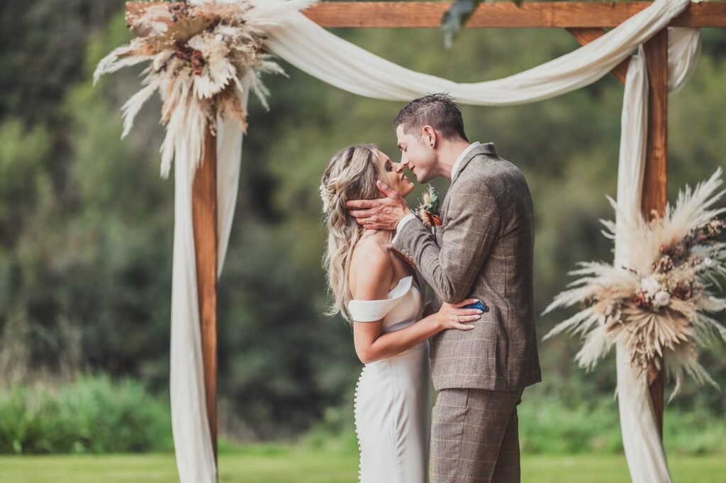 Couple kissing under a dried flower arch at Kilminorth Cottages.